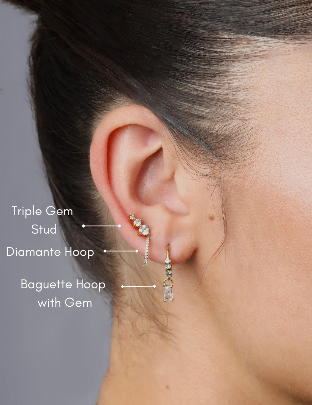 model wearing gold stud with three sparkly gemstones in a line 