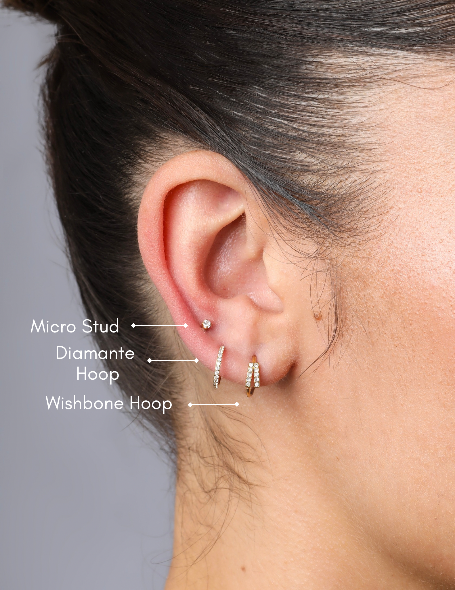 model wearing gold wishbone hoop with two lines of sparkly gemstones along the wishbone