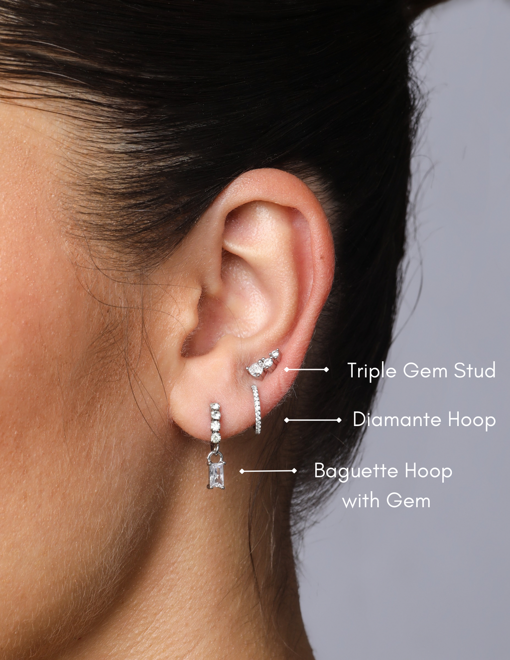 model wearing silver hoop with four sparkly baguette gemstones and dangling wishbone hoop