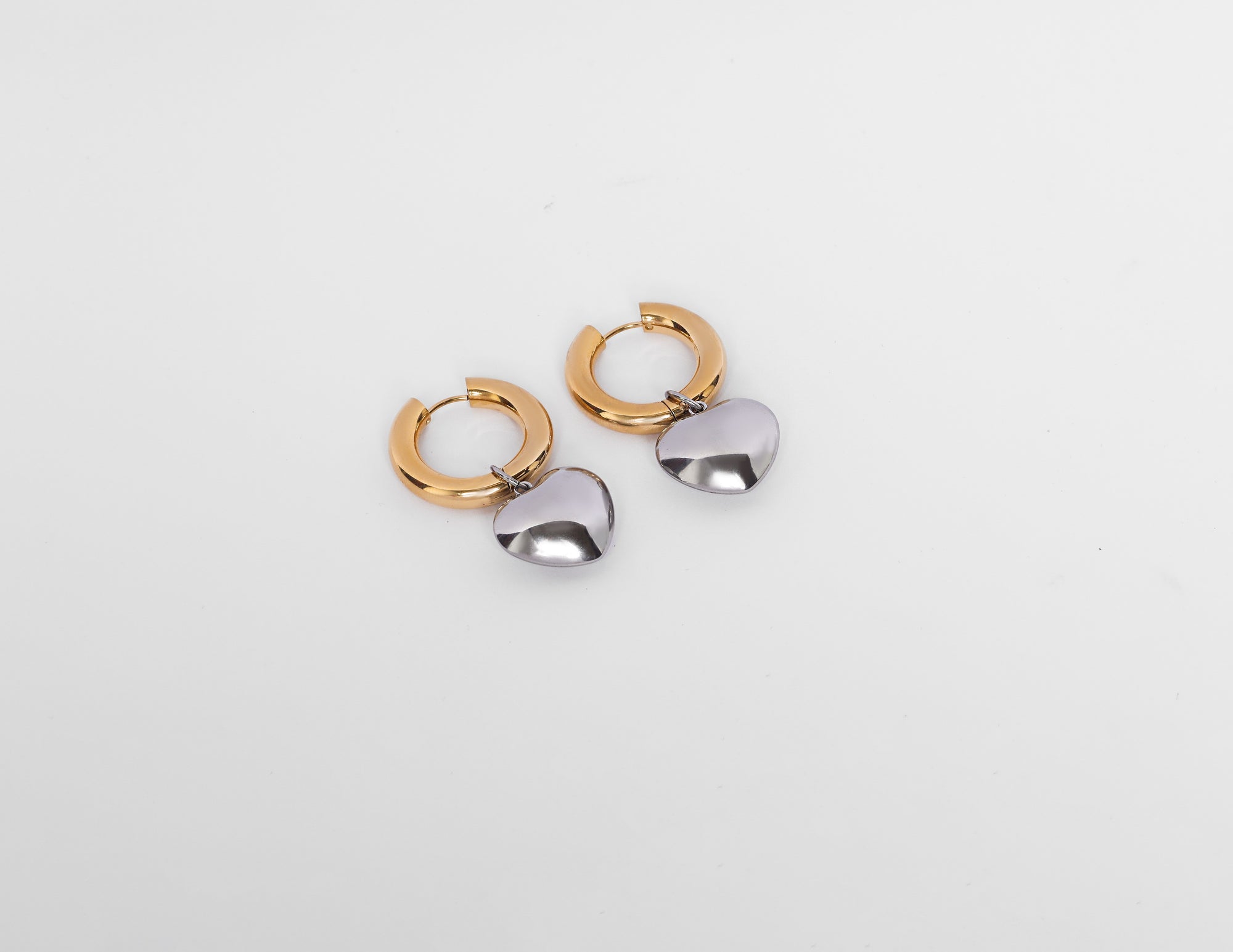 Chunky gold hoop earrings with silver heart charms – moody mixed-metal statement jewellery